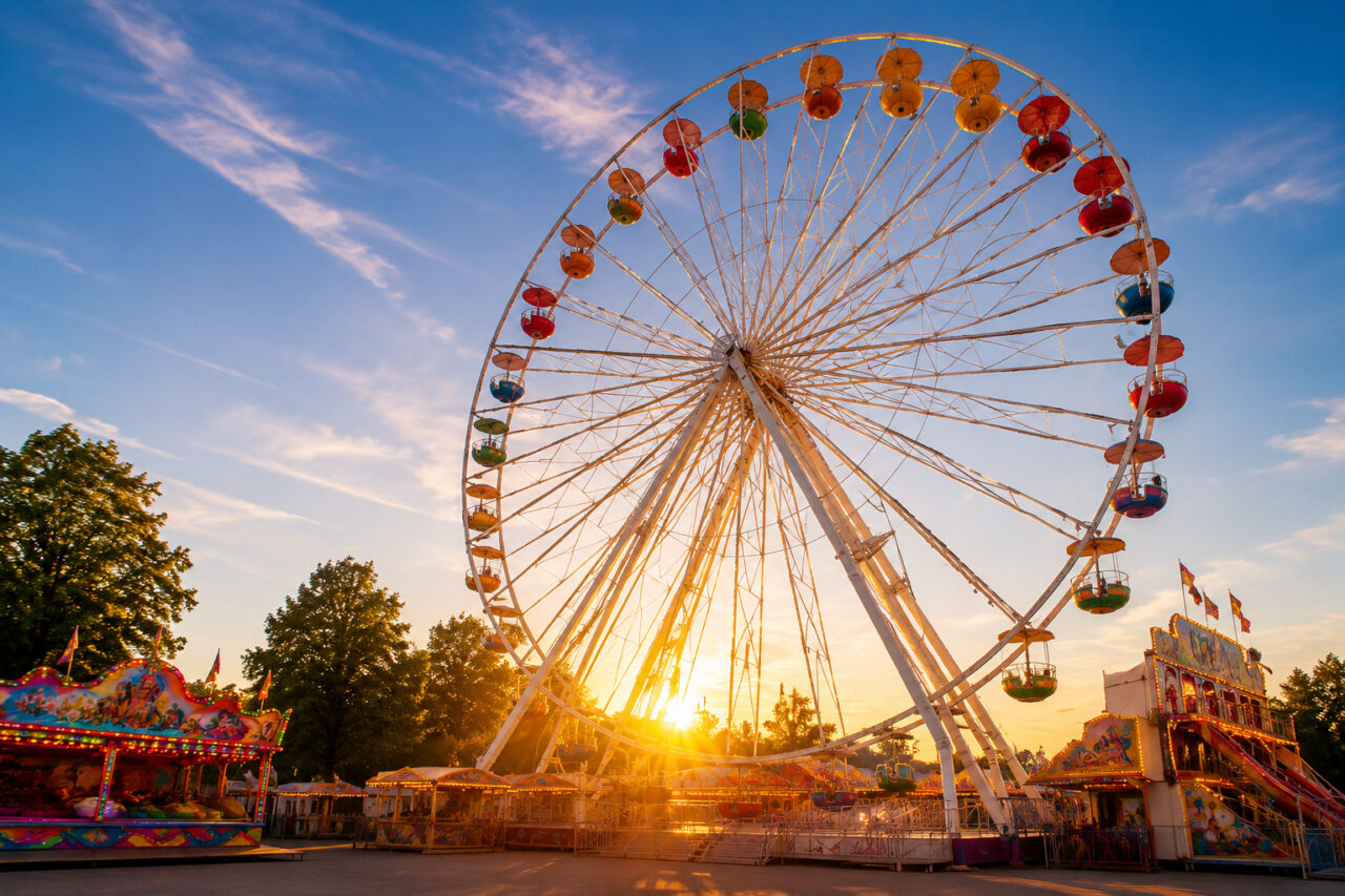Riesenrad und Besucher auf dem Welser Volksfest in Wels bei sommerlichem Abendlicht.